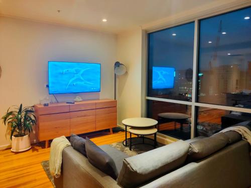 a living room with a couch and a flat screen tv at Adelaide Central Skyline Panoramic Suite in Adelaide
