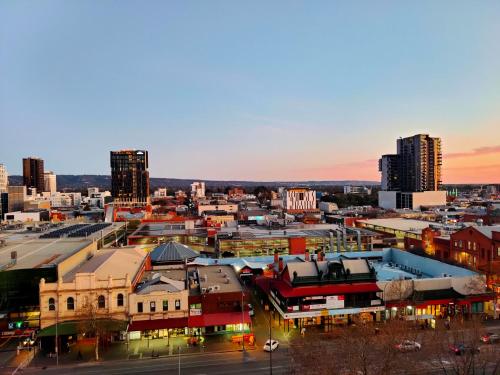 a view of a city at sunset with buildings at Adelaide Central Skyline Panoramic Suite in Adelaide