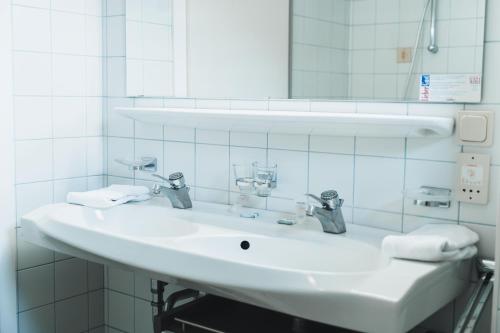 a bathroom with a white sink and a mirror at Hotel Rauscher - Das Naturteichparadies in Bad Hofgastein