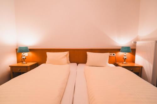 two beds in a room with two lamps on tables at Hotel Rauscher - Das Naturteichparadies in Bad Hofgastein