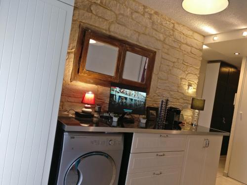 une buanderie avec un lave-linge et un mur en pierre dans l'établissement T2 centre ville parking 19 thonon-o-phil-de-l-eau, à Thonon-les-Bains