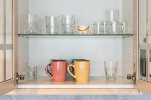 a shelf with two cups and glasses on it at Modern & Spacious 2-Bed Condo with Panoramic Lake Views, Dual Balconies, Steps from Dubai JLT Metro By "La Buena Vida Holiday Homes" in Dubai