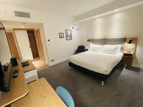 a hotel room with a bed and a desk at Holiday Inn Dijon Sud - Longvic by IHG in Dijon