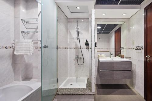 a bathroom with a shower and a sink and a tub at Modern & Spacious 2-Bed Condo with Panoramic Lake Views, Dual Balconies, Steps from Dubai JLT Metro By "La Buena Vida Holiday Homes" in Dubai
