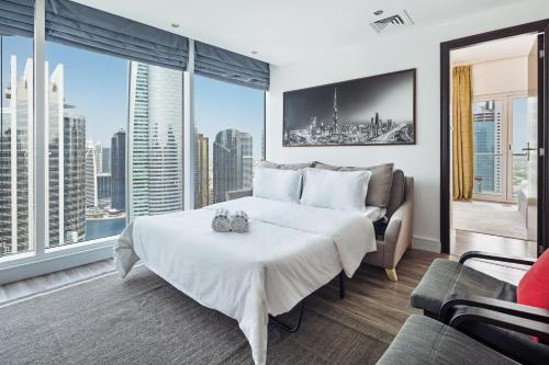 a bedroom with a large white bed and a couch at Modern & Spacious 2-Bed Condo with Panoramic Lake Views, Dual Balconies, Steps from Dubai JLT Metro By "La Buena Vida Holiday Homes" in Dubai