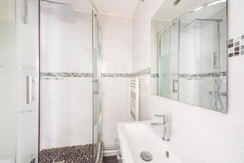 une salle de bain blanche avec une douche et un lavabo dans l'établissement Magnifique appartement Paris, à Boulogne-Billancourt