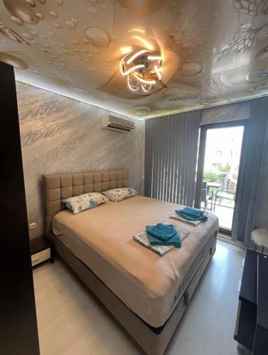 a bedroom with a bed and a ceiling with a chandelier at Менада Хоризонт Апартаменти in Sozopol