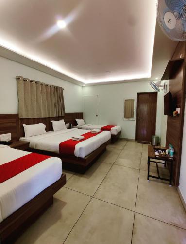 a hotel room with three beds and a table at 100 Oaks Estate in Yercaud