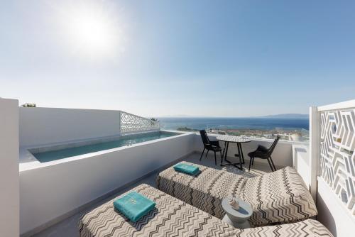 a balcony with two beds and a table with chairs at La Madeleine Oia in Oia