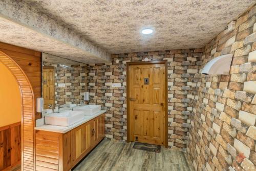 a bathroom with two sinks and a stone wall at Zostel Kotgarh, Narkanda in Kotgarh