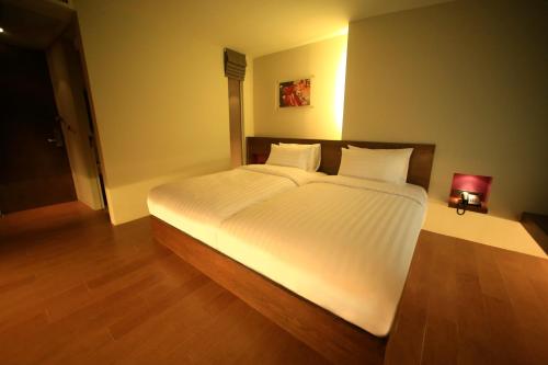 a bedroom with a large bed with white sheets at Silom One in Bangkok