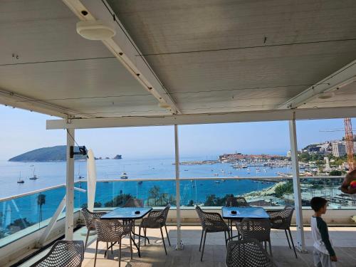 a patio with tables and chairs and a view of the ocean at Apartments Menuet in Budva