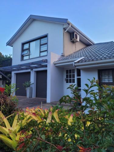 a white house with black windows and bushes at Suite 10- Deja' Blu Bed and Breakfast- East London in East London