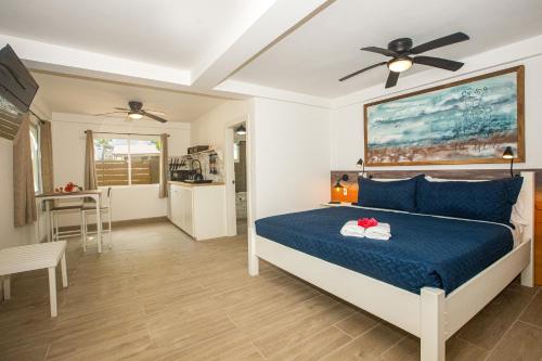 a bedroom with a bed with blue sheets and a ceiling fan at Treetops Hotel in Caye Caulker