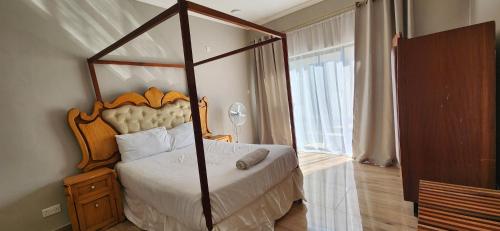 a bedroom with a canopy bed and a window at Chinyonga Guesthouse in Limbe