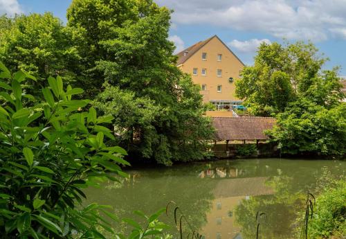 a building next to a body of water with trees at B&B HOTEL Chartres Centre Cathédrale 3 étoiles in Chartres