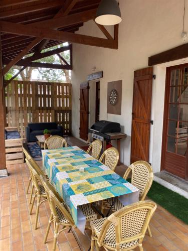 un patio avec une table, des chaises et un barbecue dans l'établissement Maison landaise au cœur de Moliets, à Moliets-et-Maa