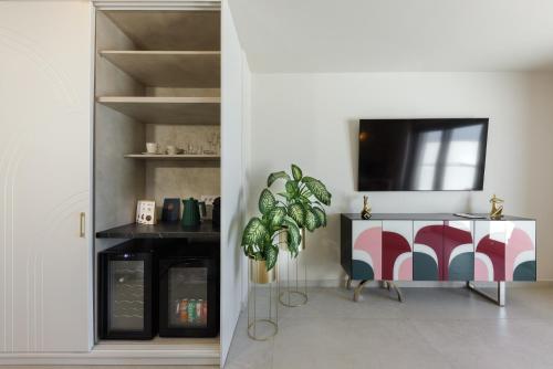 a living room with a tv and a table with a plant at La Madeleine Oia in Oia