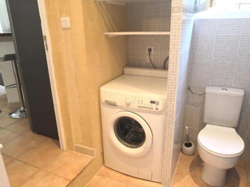 une petite salle de bains avec un lave-linge et des toilettes. dans l'établissement Studio avec piscine privée à 5 minutes de la mer, à Saint-Paul-de-Vence