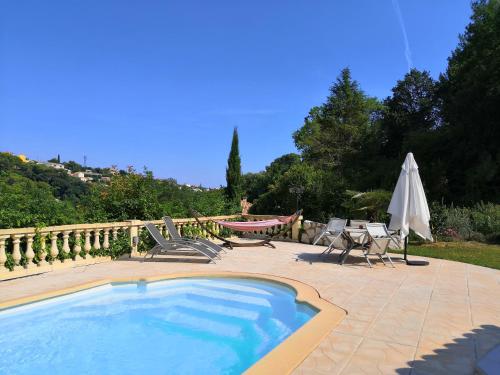 une piscine avec des chaises et un parasol dans l'établissement Studio avec piscine privée à 5 minutes de la mer, à Saint-Paul-de-Vence