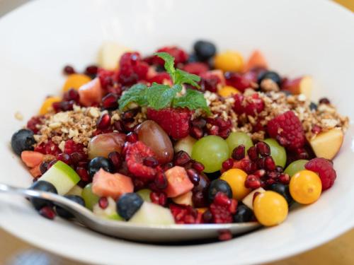 a white plate of fruit salad with a spoon at Mediterranean Villa Guesthouse in Cape Town