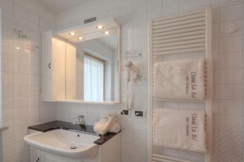 a white bathroom with a sink and a mirror at Ciasa La Ro in San Cassiano