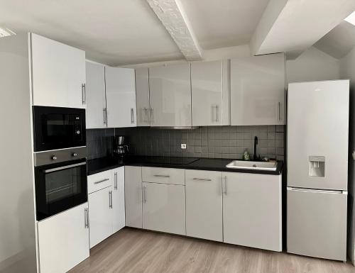 - une cuisine blanche avec des armoires blanches et des appareils noirs dans l'établissement L'Amazonite, au Beausset