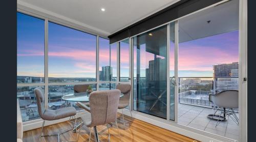 a room with glass windows and a table and chairs at Adelaide Central Skyline Panoramic Suite in Adelaide