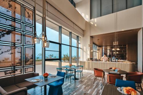 a restaurant with tables and chairs and large windows at Hotel Indigo Yantai Golden Coast by IHG in Yantai