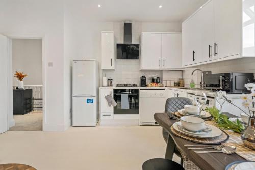 a kitchen with white cabinets and a wooden table at London Wembley Luxury Stay 2BR Apartment next to stadium with Free Parking in London
