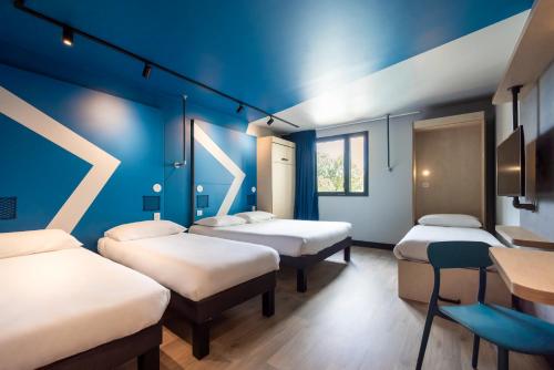 a room with four beds and a blue wall at ibis Budget La Rochelle Centre gare in La Rochelle