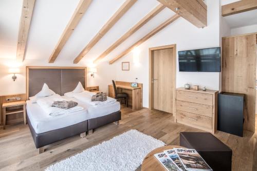 a bedroom with a large bed and a desk at Sporthotel Zoll in Vipiteno
