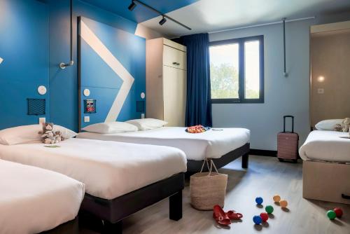a room with three beds with blue walls at ibis Budget La Rochelle Centre gare in La Rochelle