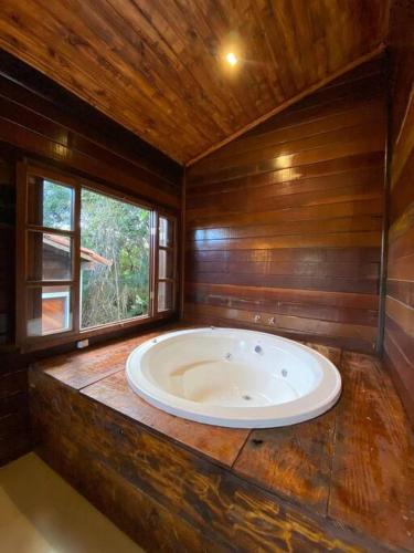 a large bath tub in a room with a window at Encanto da Mata - Jacarandá - Lavras Novas-MG in Lavras Novas