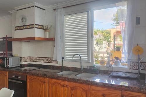 a kitchen with two sinks and a large window at Golden Beach in Xeraco