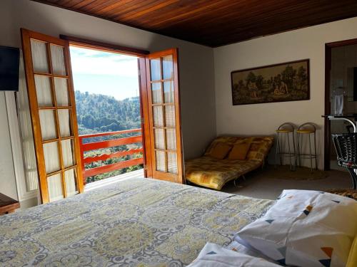 ein Schlafzimmer mit einem Bett, einem Fenster und einer Couch in der Unterkunft sonho de valsa in Campos do Jordão