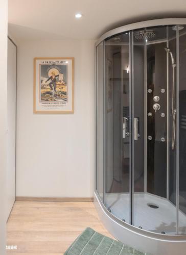 une douche en verre dans une pièce avec un tableau au mur dans l'établissement Hypercentre, authentique, calme - La distillerie, à Pontarlier