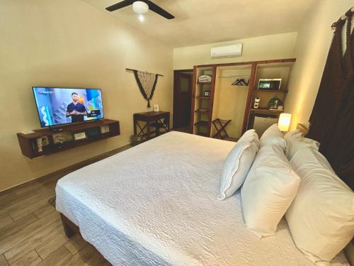 a bedroom with a bed with pillows and a flat screen tv at Aldea Xaan Ha Tulum in Tulum