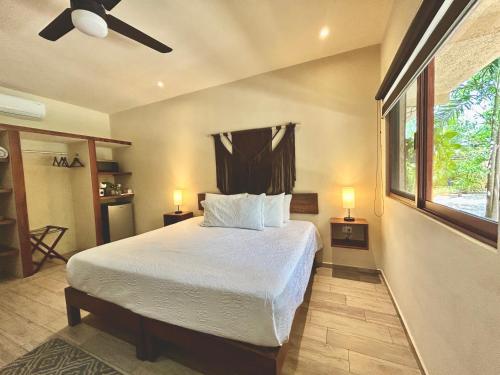 a bedroom with a bed with a ceiling fan and a window at Aldea Xaan Ha Tulum in Tulum