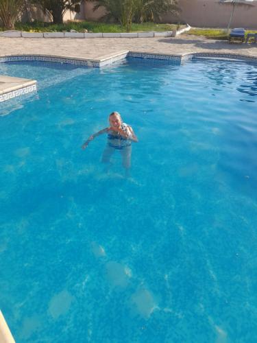 a person swimming in a pool of blue water at Residence Nour douz in Douz