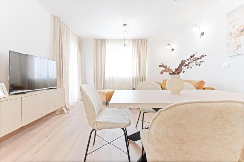 a white dining room with a white table and chairs at Lush Suites in Trogir