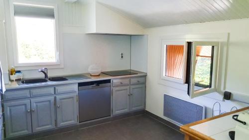 une cuisine avec des armoires blanches, un évier et une fenêtre dans l'établissement Agréable T3 entre lac et montagne, à Verchères