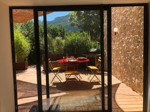 une porte en verre menant à une terrasse avec une table et des chaises. dans l'établissement Métairie la Faurie Drôme, à Aurel