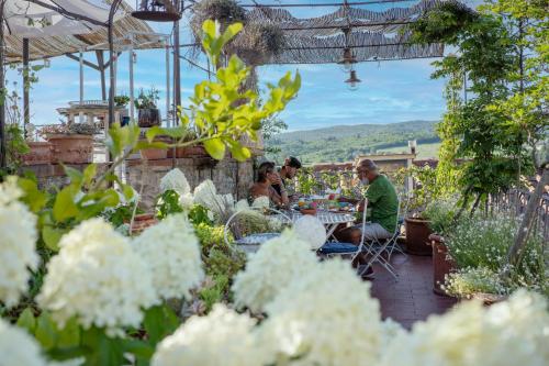 a group of people sitting at a table in a garden at Le Terrazze Del Chianti b&b Residenza d'Epoca e di Charme in Tavarnelle in Val di Pesa