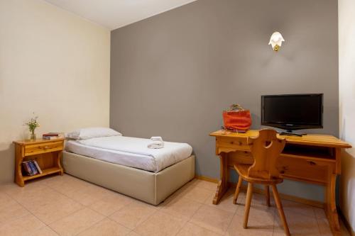 una camera da letto con un letto e una scrivania con una televisione di Agritur Eden Marone a Riva del Garda