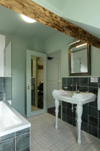 a bathroom with two sinks and a tub and a mirror at Hôtel du Château Bois Guibert in Bonneval