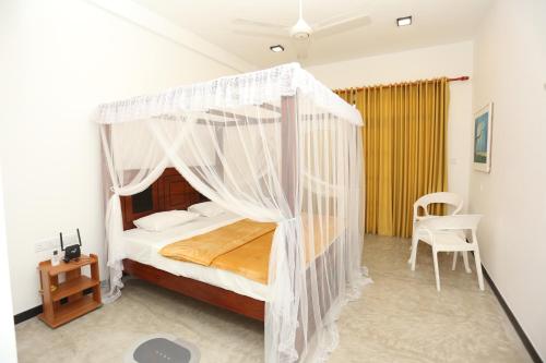 a bedroom with a white canopy bed with a chair at Sisi's Place in Bentota