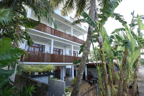 a building with palm trees in front of it at Sisi's Place in Bentota