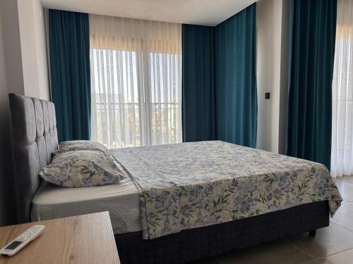 a bedroom with a bed and a window with blue curtains at Villa Ögreten in Aydın