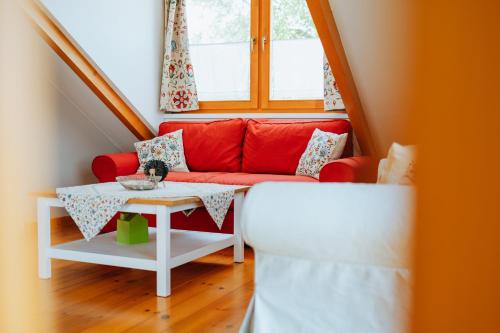 a living room with a red couch and a table at Penzion U maléřa in Hroznová Lhota